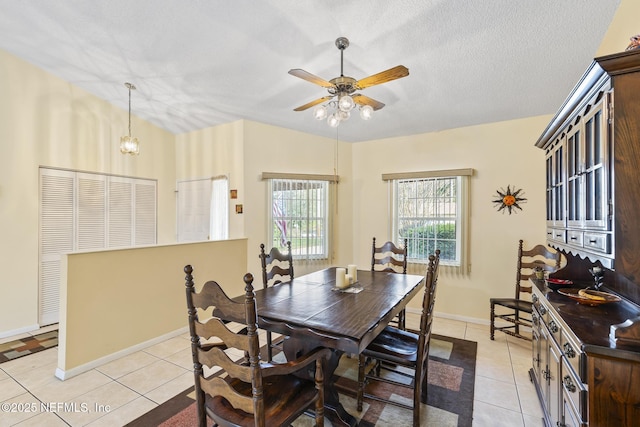 dining space with lofted ceiling, ceiling fan with notable chandelier, a textured ceiling, and light tile patterned floors