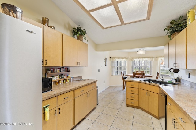 kitchen with light tile patterned floors, dishwashing machine, a peninsula, a sink, and light countertops