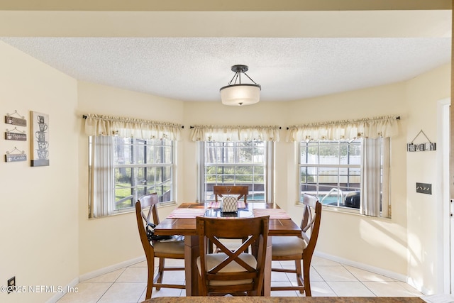 dining room with a healthy amount of sunlight, light tile patterned floors, baseboards, and a textured ceiling