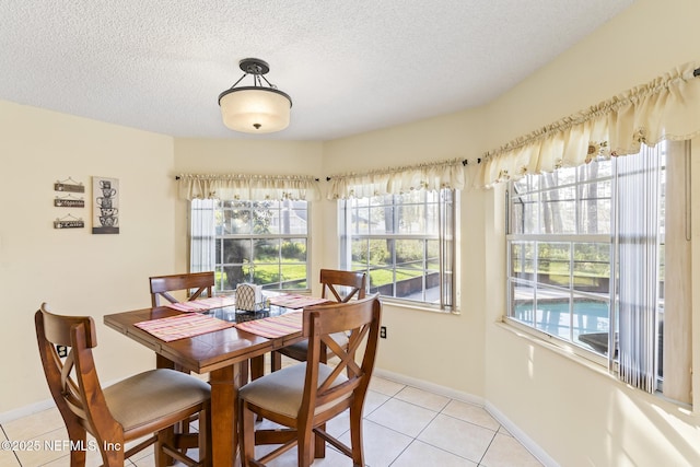 dining area with a textured ceiling, baseboards, and light tile patterned floors