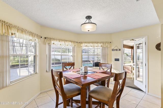 dining room featuring light tile patterned floors, a textured ceiling, and baseboards