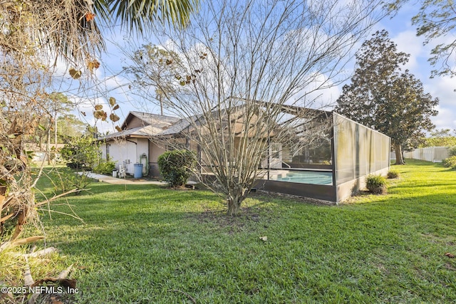 exterior space with a lanai, a fenced in pool, a lawn, and stucco siding