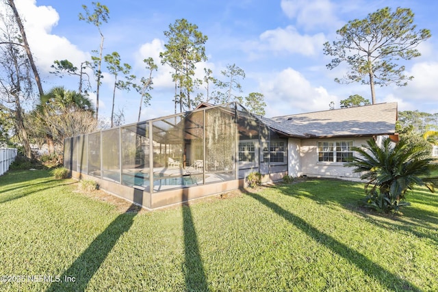 back of property with a lanai, fence, an outdoor pool, and a lawn