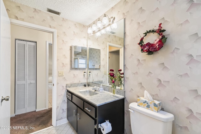 bathroom featuring wallpapered walls, visible vents, toilet, a textured ceiling, and a closet