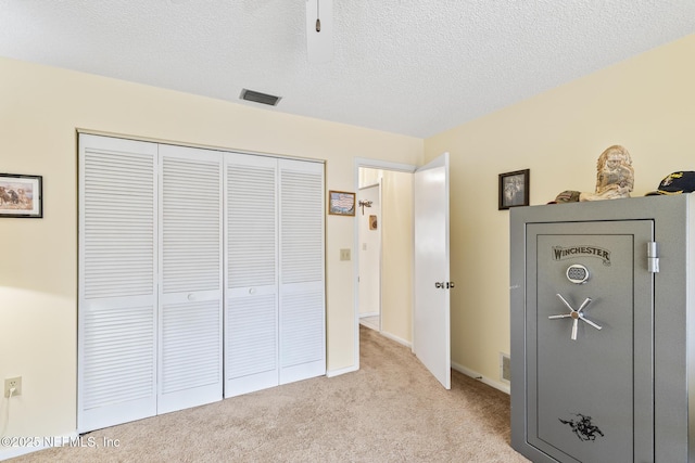 unfurnished bedroom with a textured ceiling, visible vents, a closet, and light colored carpet