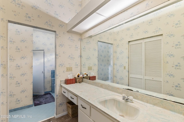 bathroom with wallpapered walls, tile patterned floors, baseboards, and vanity