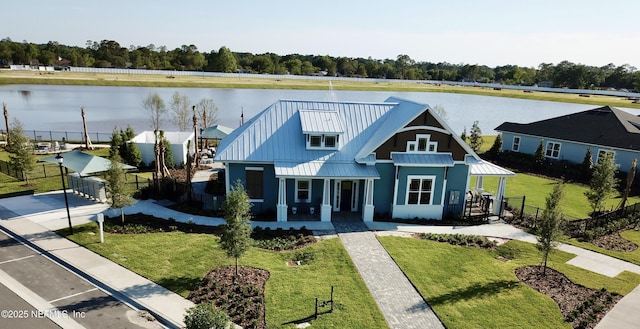 modern inspired farmhouse featuring covered porch, a water view, a standing seam roof, metal roof, and a front lawn