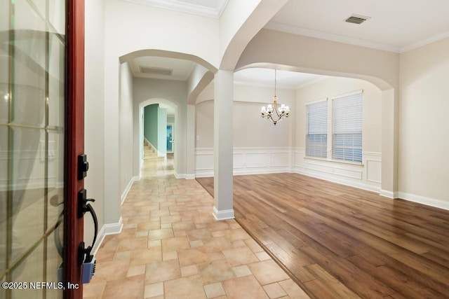 foyer entrance featuring a notable chandelier, visible vents, light wood-type flooring, and crown molding