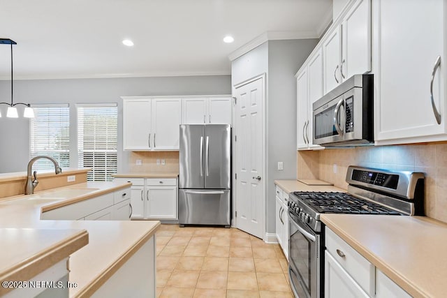 kitchen with a sink, appliances with stainless steel finishes, ornamental molding, and light countertops