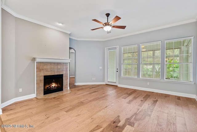 unfurnished living room featuring a fireplace, wood finished floors, baseboards, and ornamental molding