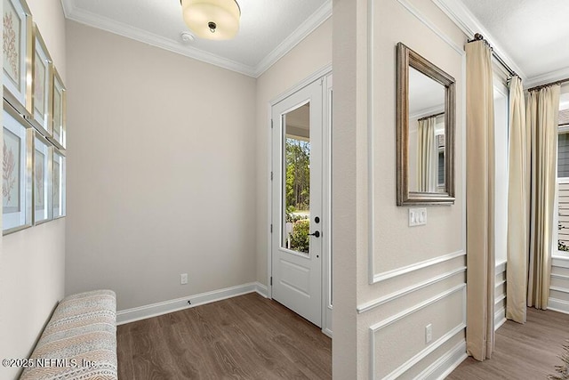 interior space featuring baseboards, wood finished floors, and crown molding