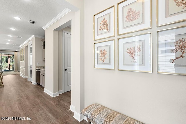 corridor featuring visible vents, baseboards, ornamental molding, a textured ceiling, and dark wood-style flooring