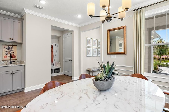 dining area with dark wood-style floors, baseboards, visible vents, ornamental molding, and a notable chandelier