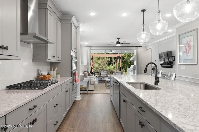 kitchen featuring wall chimney range hood, gray cabinetry, appliances with stainless steel finishes, and a sink