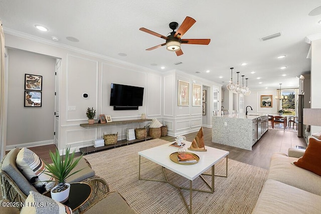 living area featuring a decorative wall, dark wood-style flooring, visible vents, and ornamental molding