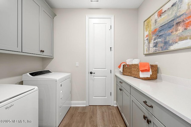 laundry room featuring visible vents, baseboards, wood finished floors, cabinet space, and independent washer and dryer