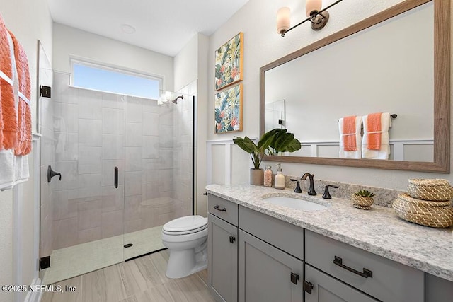 bathroom featuring tiled shower, toilet, and vanity