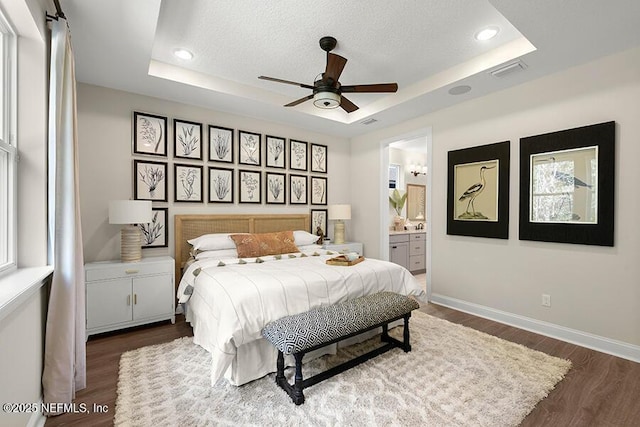 bedroom with a raised ceiling, baseboards, and dark wood-type flooring