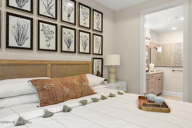 bedroom with ensuite bath, baseboards, and wood finished floors