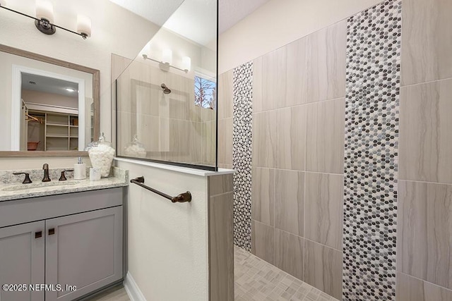 bathroom featuring vanity, a walk in closet, and walk in shower