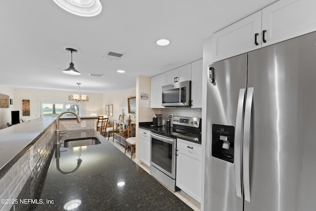 kitchen featuring a sink, decorative backsplash, stainless steel appliances, pendant lighting, and white cabinetry