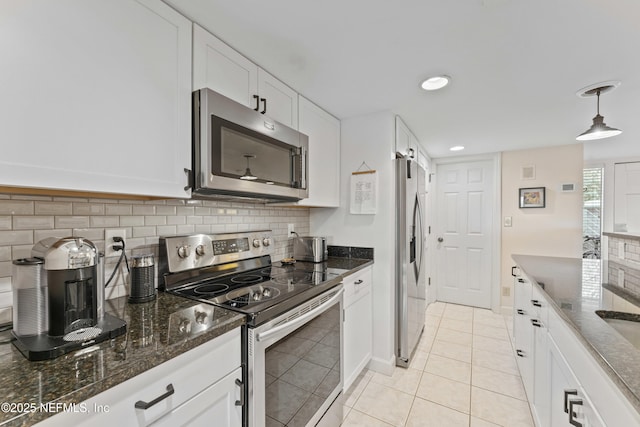 kitchen with backsplash, appliances with stainless steel finishes, white cabinetry, and dark stone counters