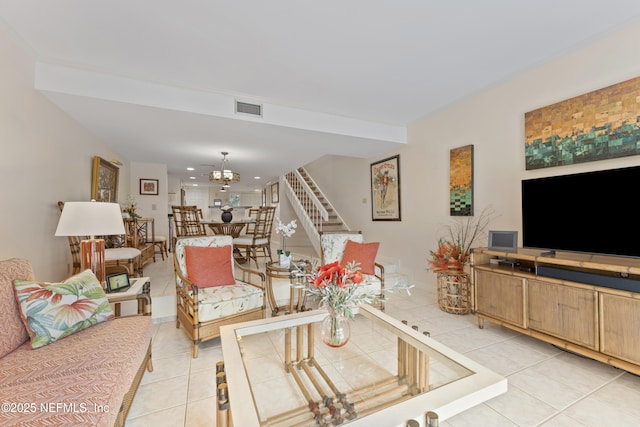 living area featuring light tile patterned floors, visible vents, stairway, and a chandelier