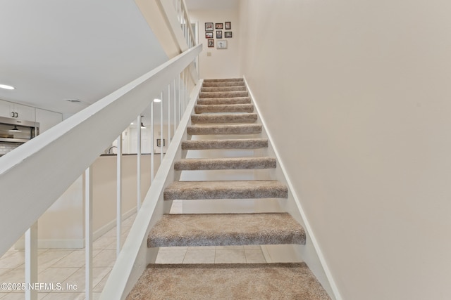 staircase featuring tile patterned floors and baseboards