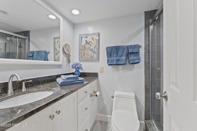 bathroom with baseboards, vanity, toilet, and a shower stall