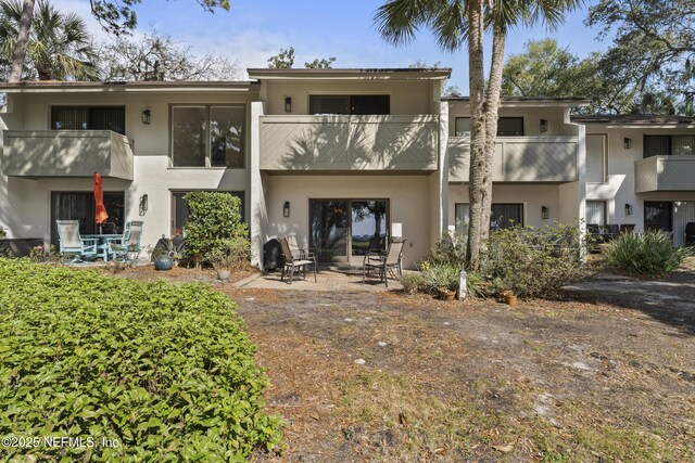 back of house featuring a balcony, stucco siding, and a patio