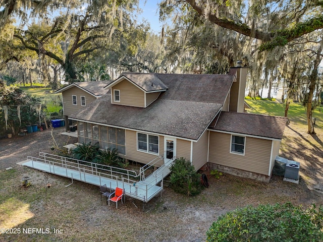 view of front of property with a sunroom, a shingled roof, and a chimney