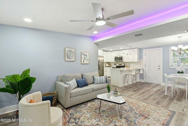 living room with light wood finished floors, baseboards, and visible vents