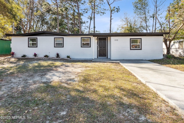 single story home with concrete block siding and a front lawn