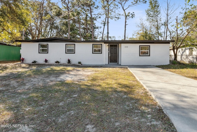 single story home with concrete block siding and fence