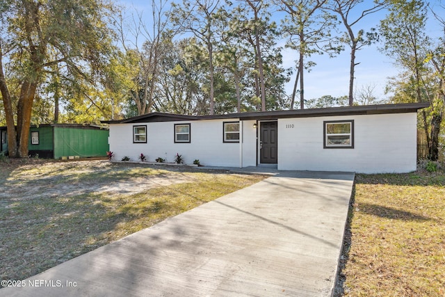 single story home with concrete block siding and a front lawn