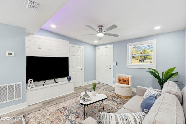 living area with recessed lighting, wood finished floors, visible vents, and baseboards