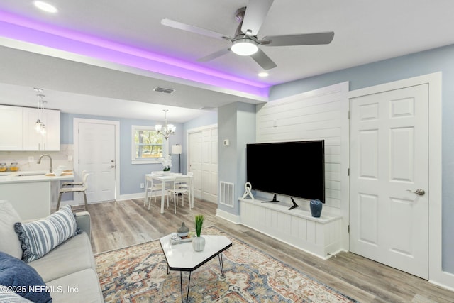 living area with light wood-type flooring, visible vents, and baseboards