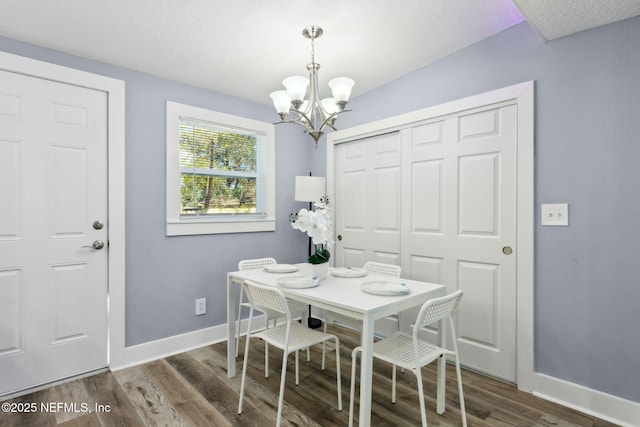 dining space featuring a chandelier, dark wood finished floors, and baseboards