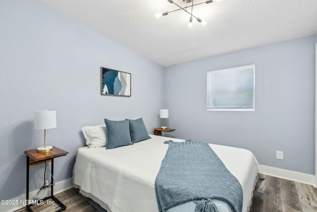 bedroom featuring a textured ceiling, baseboards, and wood finished floors