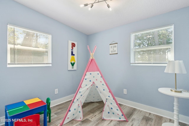 recreation room featuring baseboards and wood finished floors