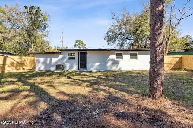 rear view of property featuring fence and a lawn