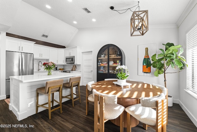 dining room featuring vaulted ceiling, dark wood-type flooring, a textured ceiling, and visible vents