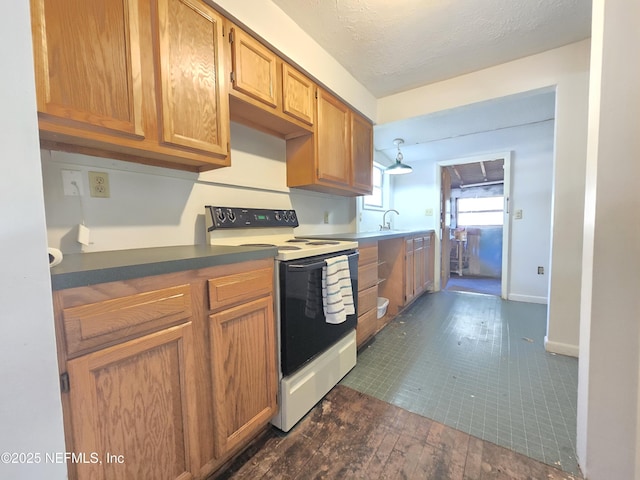 kitchen with dark wood-style floors, range with electric stovetop, a sink, a textured ceiling, and baseboards