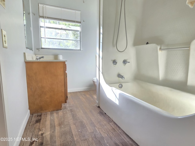 bathroom featuring shower / bathtub combination, toilet, vanity, baseboards, and hardwood / wood-style flooring