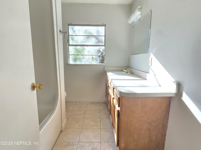 full bath featuring a bathtub, toilet, vanity, tile patterned flooring, and baseboards