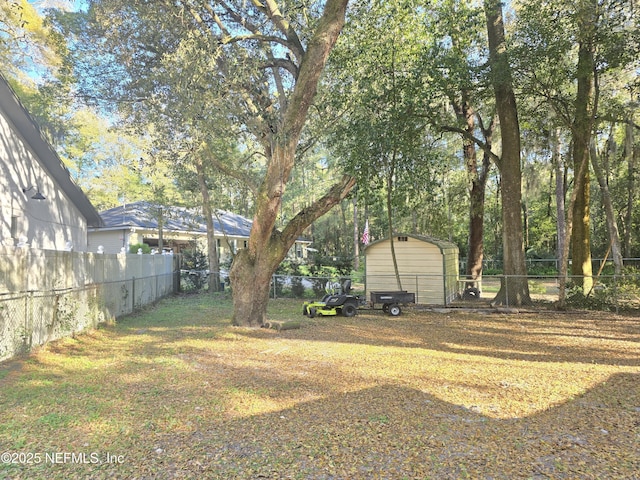 view of yard with a detached carport, a fenced backyard, an outdoor structure, and a storage shed