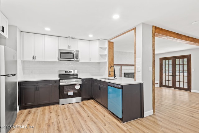 kitchen with stainless steel appliances, white cabinetry, a sink, and open shelves