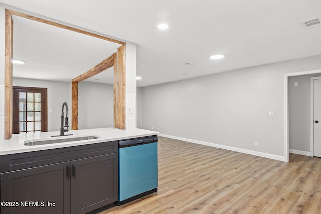 kitchen with dishwasher, light countertops, a sink, and light wood-style flooring