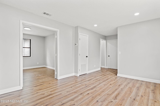 unfurnished room featuring light wood finished floors, visible vents, and baseboards