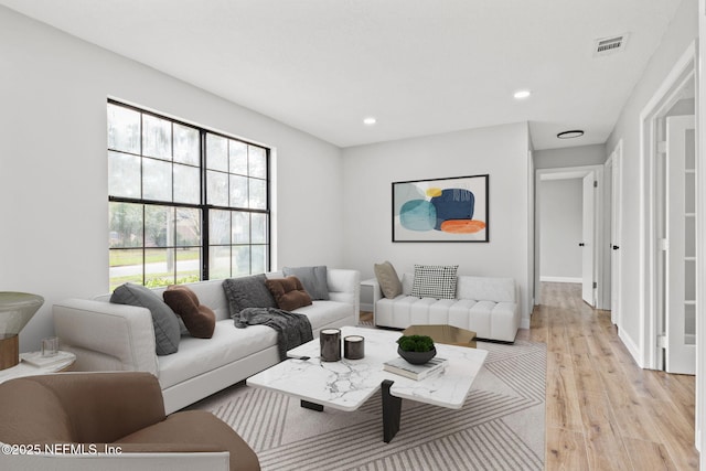 living area with baseboards, light wood-type flooring, visible vents, and recessed lighting